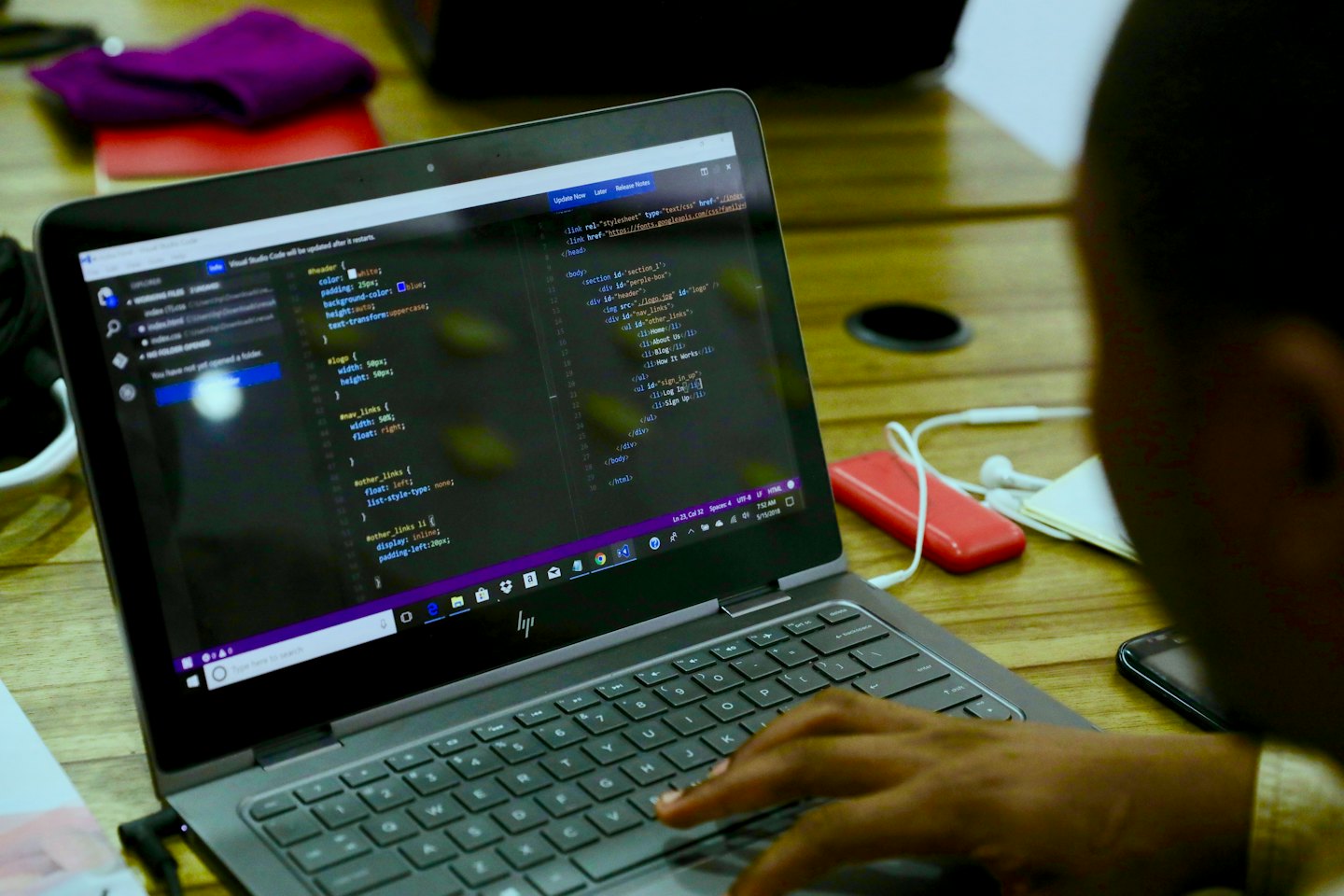 Persona che scrive codice HTML e CSS su un laptop a una scrivania.